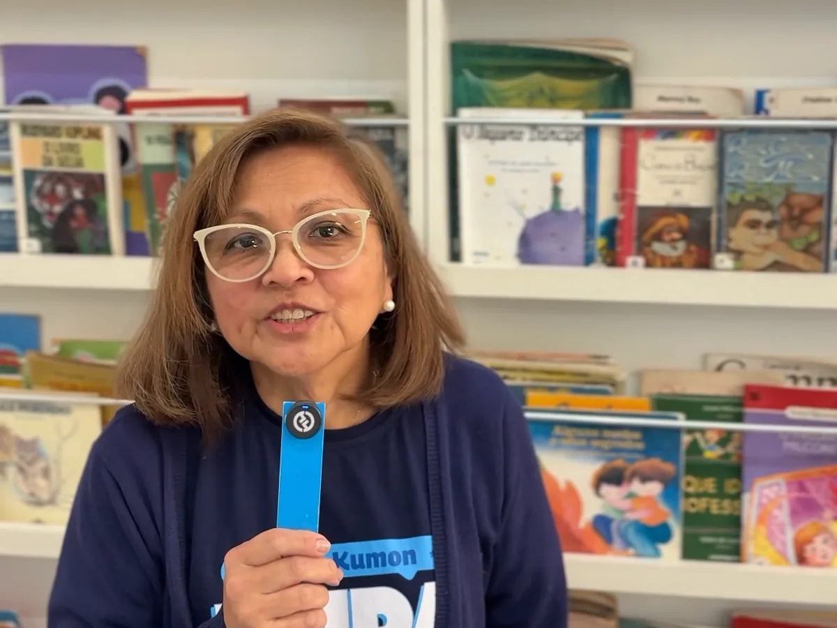 Kumon instructor holding a bookmark in front of a bookshelf, from a Kumon social video